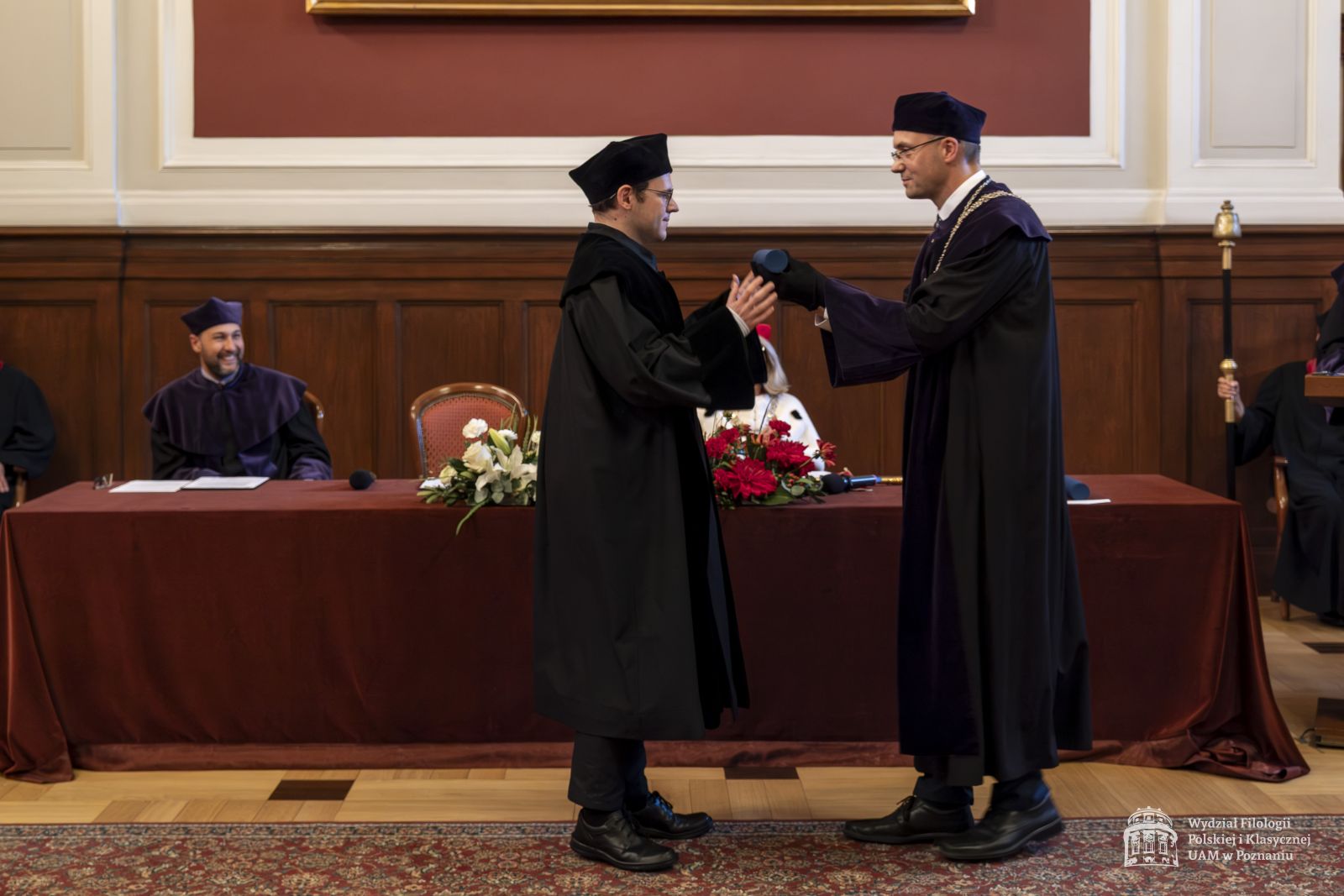 Dziekan WFPiK wręcza doktorantowi dyplom w zastępstwie nieobecnego promotora.
