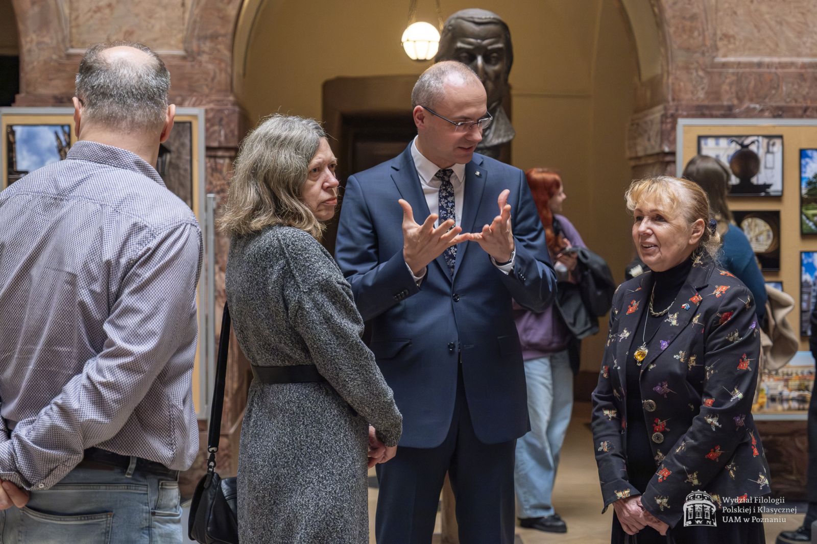 Dziekan WFPiK rozmawia w holu głównym z Konsul Honorową Czech Renatą Mataczyńską i wicedyrektor IFS prof. Anną Gawarecką, za nimi widać sztalugi z wystawą.
