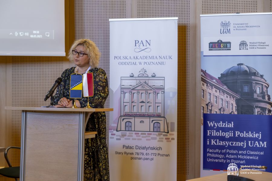 Prof. Ewa Szperlik przemawia przy mównicy, na pulpicie przed nią stoją małe flagi Polski i Bośni i Hercegowiny, za nią dwa roll-upy: Polskiej Akademii Nauk Oddziału w Poznaniu i wydziałowy.