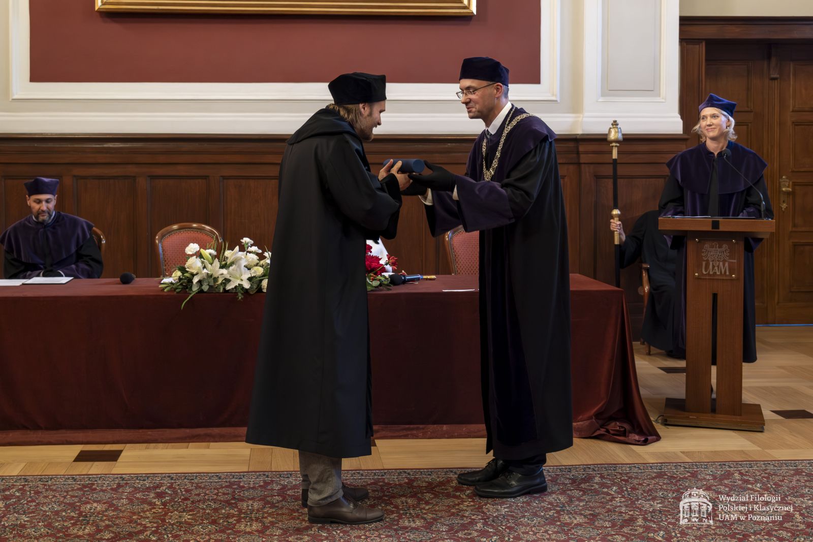 Dziekan WFPiK wręcza doktorantowi dyplom w zastępstwie nieobecnego promotora.