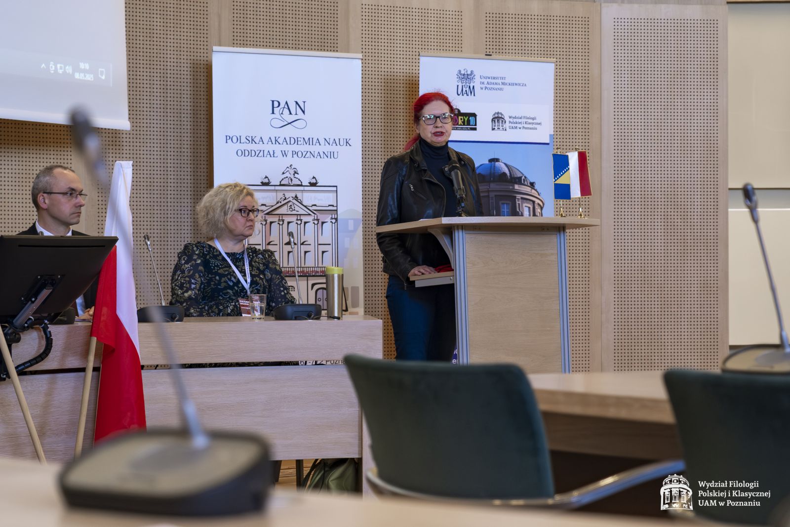 Dyrektorka Teatru im. Aleksandra Fredry w Gnieźnie Joanna Nowak przemawia przy mównicy, obok niej widać siedzących prof. Ewę Szperlik i prof. Krzysztofa Skibskiego.